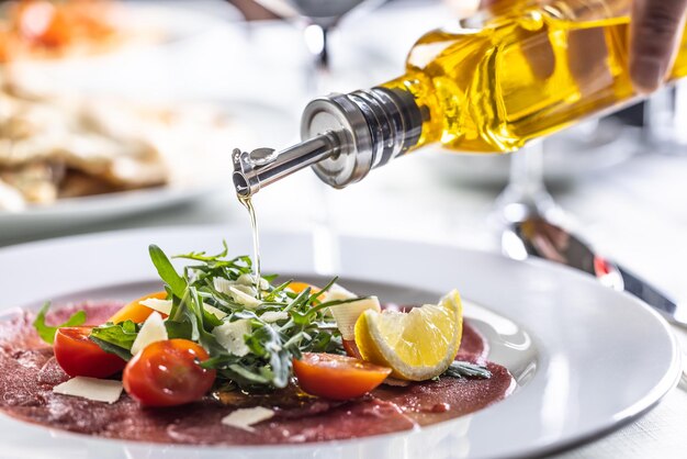 Vitalitaly Olivenöl Tumaiì über Rucola-Carpaccio gegossen – elegante italienische Vorspeise mit ligurischem Olivenöl