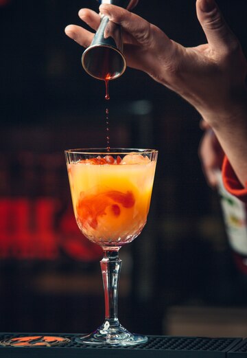 Roter Sirup wird in einen Orangen-Mocktail gegossen — alkoholfreier Spritz Balsamico-Aperitivo, erfrischend und vegan von Vitalitaly